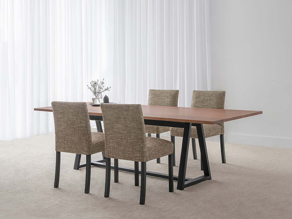 modern dining table with fabric dining chairs made in blackwood timber with a black trestle base