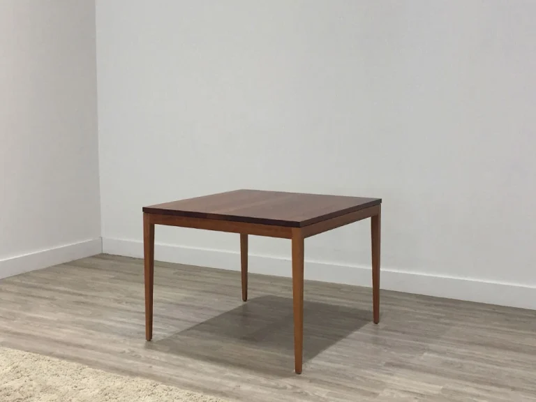 small square timber dining table with slim tapered legs and dark toned finish