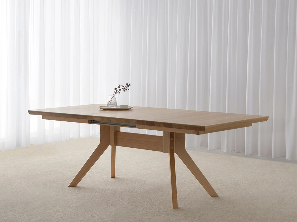 Small extendable dining table with angled leg base in solid light oak timber