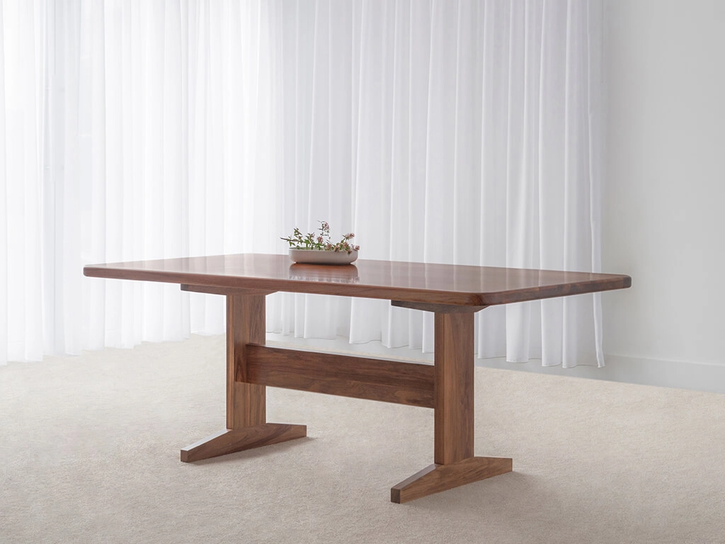 solid timber dining table in blackwood with rounded corners and traditional pedestal base