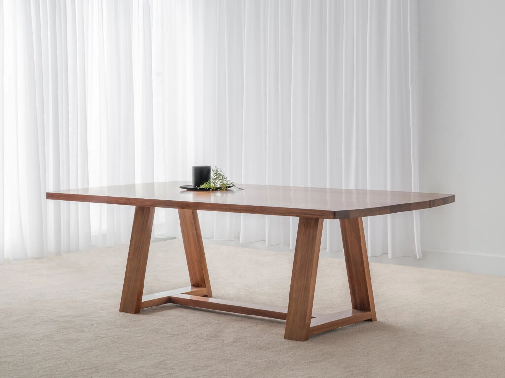 solid timber dining table with thick trestle base and rounded table ends