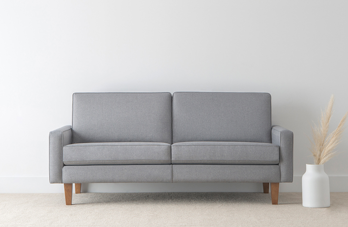 comfortable 2 seater sofa in soft blue fabric with modern square cushions and honey toned leg