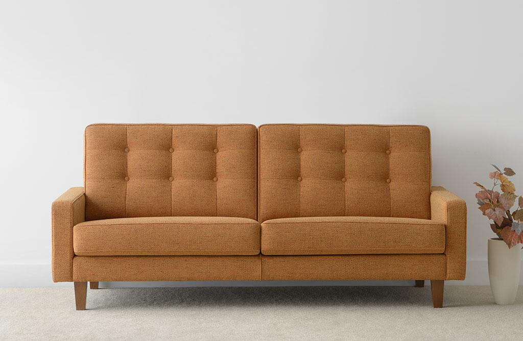 warm orange fabric sofa with button high back and timber legs